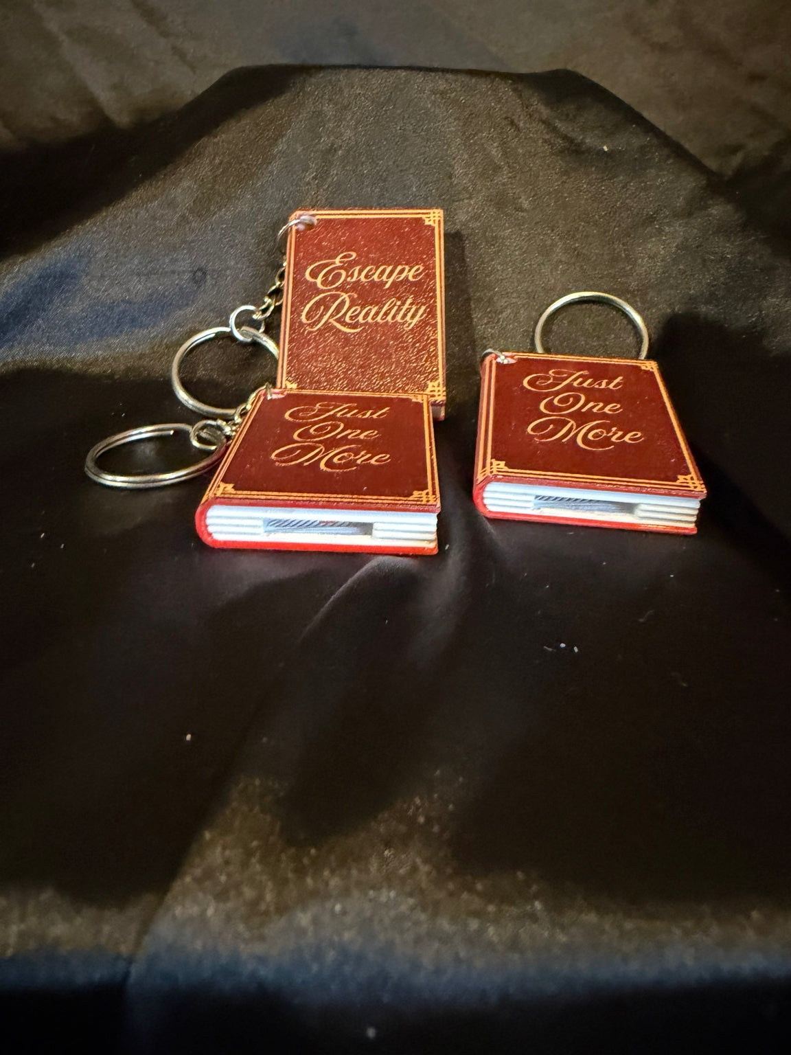 3D printed book can opener keychains shown open, assorted titles